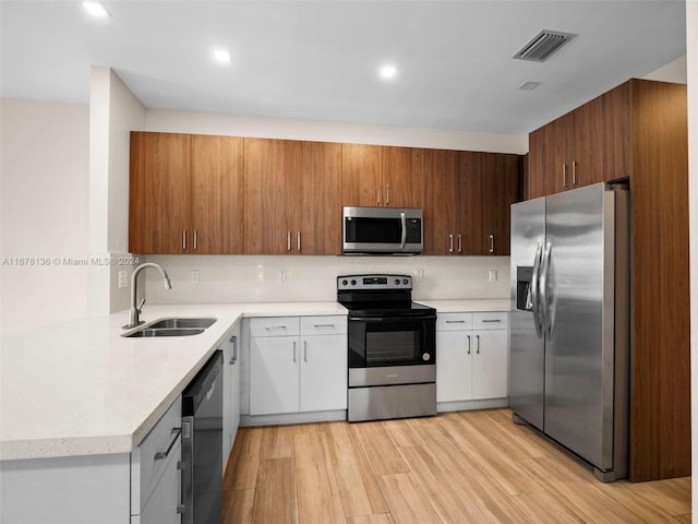 kitchen with white cabinets, light hardwood / wood-style floors, sink, and stainless steel appliances