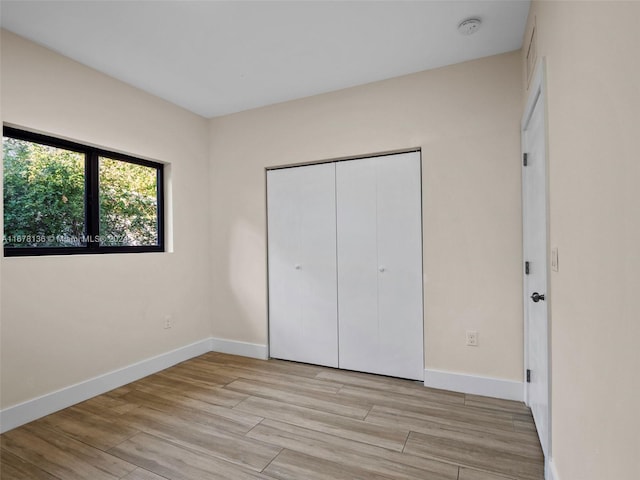 unfurnished bedroom with a closet and light hardwood / wood-style floors