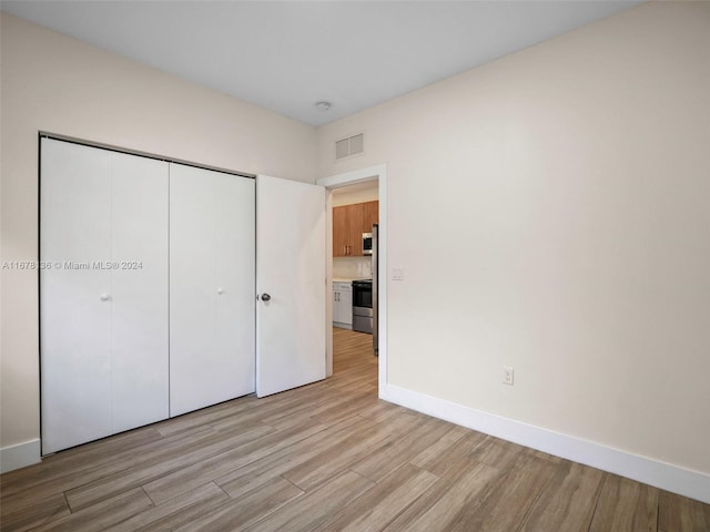 unfurnished bedroom with light hardwood / wood-style floors and a closet