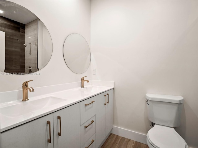 bathroom featuring hardwood / wood-style floors, vanity, toilet, and a tile shower