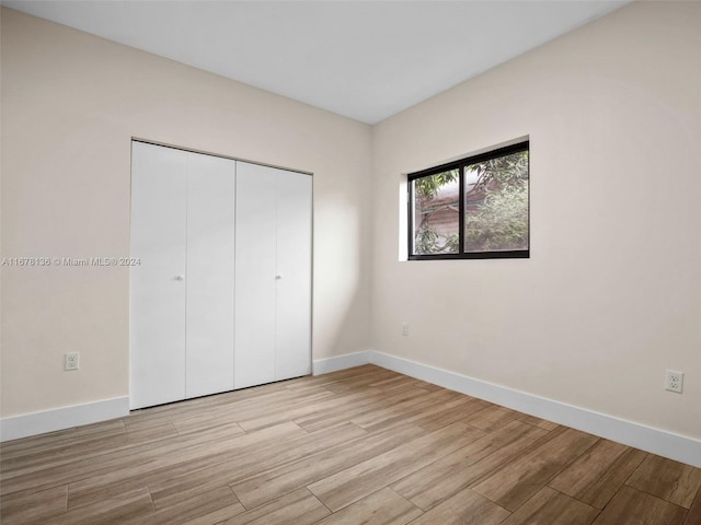 unfurnished bedroom featuring light wood-type flooring and a closet