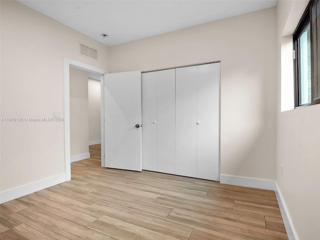 unfurnished bedroom featuring light wood-type flooring and a closet