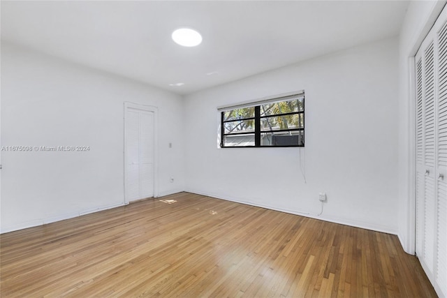 unfurnished bedroom with wood-type flooring and two closets