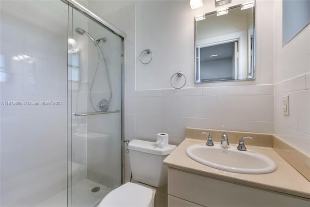 bathroom with tile walls, vanity, toilet, and an enclosed shower