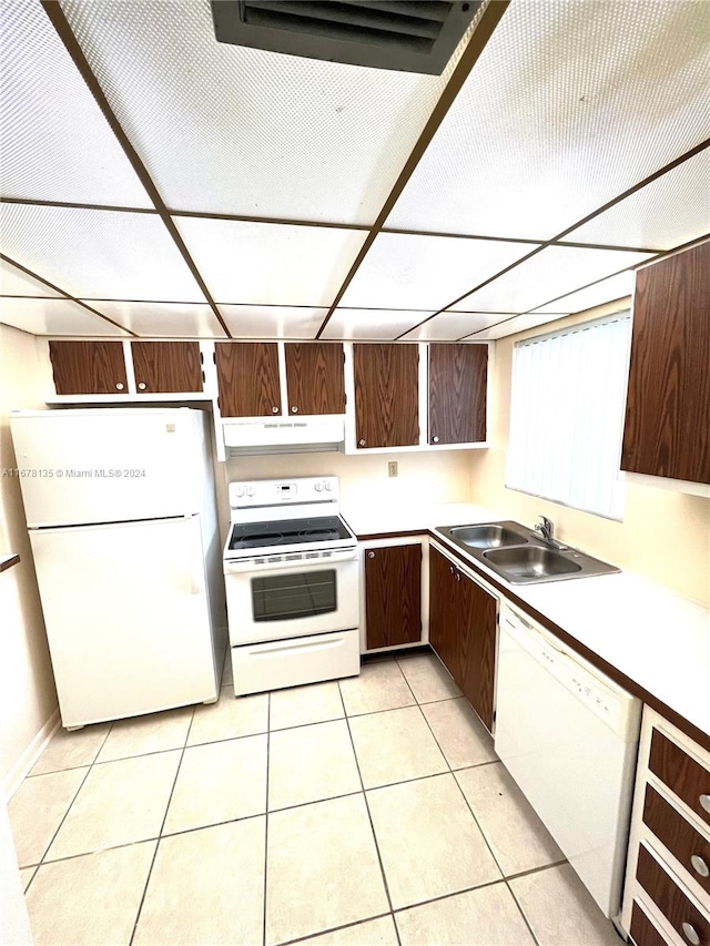 kitchen with white appliances, sink, dark brown cabinetry, range hood, and light tile patterned floors