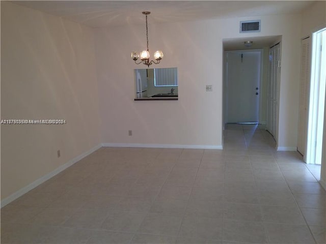 tiled empty room featuring vaulted ceiling and an inviting chandelier