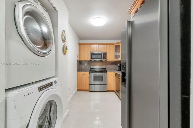 washroom with light tile patterned flooring and stacked washer and dryer