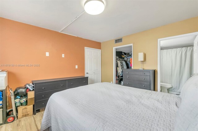 bedroom with a closet, ensuite bathroom, light hardwood / wood-style flooring, and a walk in closet