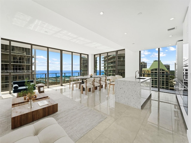 living room with light tile patterned flooring, a wall of windows, a water view, and visible vents