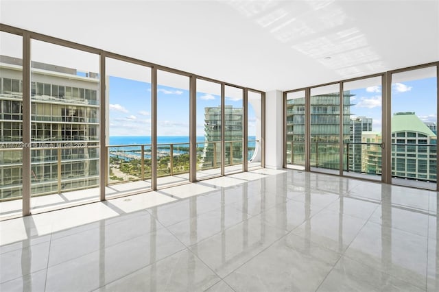 tiled spare room featuring a water view and floor to ceiling windows