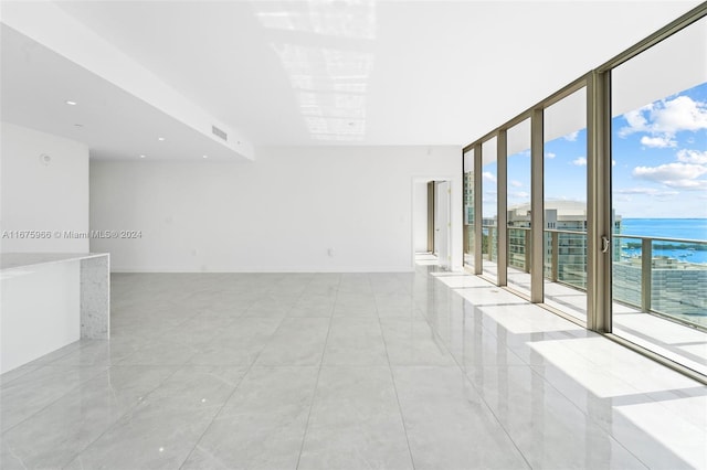 tiled empty room featuring a wall of windows and a water view