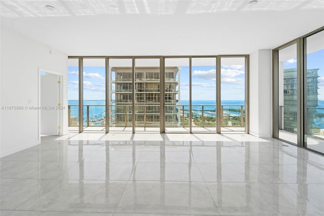 empty room with plenty of natural light, a water view, and a wall of windows