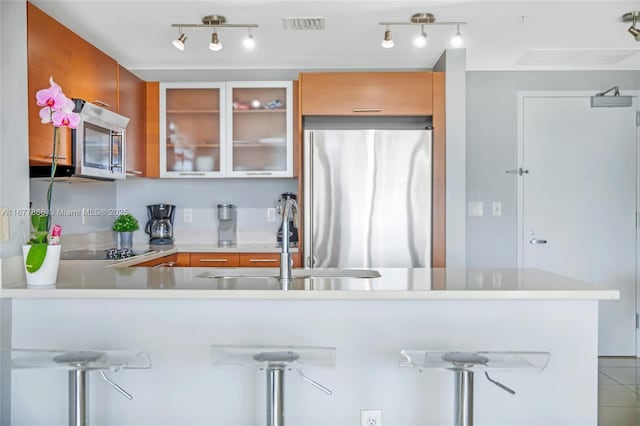 kitchen featuring tile patterned flooring, appliances with stainless steel finishes, kitchen peninsula, and sink