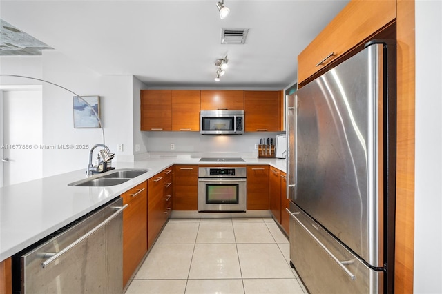 kitchen with appliances with stainless steel finishes, rail lighting, sink, and light tile patterned floors