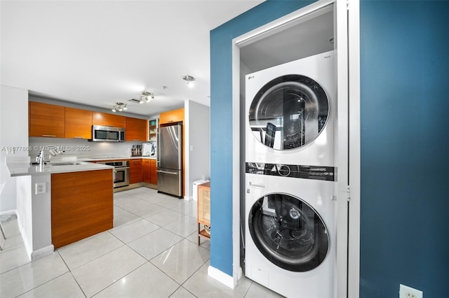 laundry area featuring stacked washer / dryer, sink, and light tile patterned floors