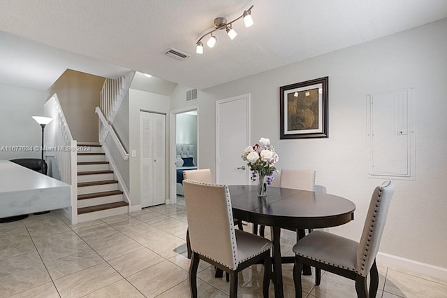 dining room with a textured ceiling, electric panel, and light tile patterned floors