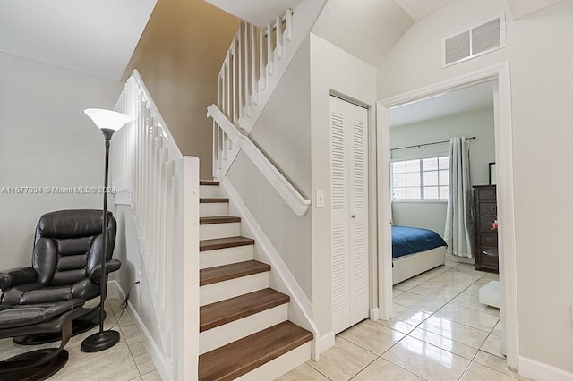 stairway with lofted ceiling and tile patterned floors