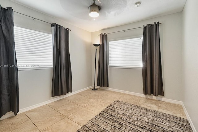 empty room with light tile patterned floors and ceiling fan