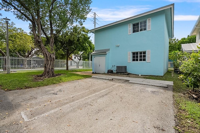 back of property featuring cooling unit and a lawn