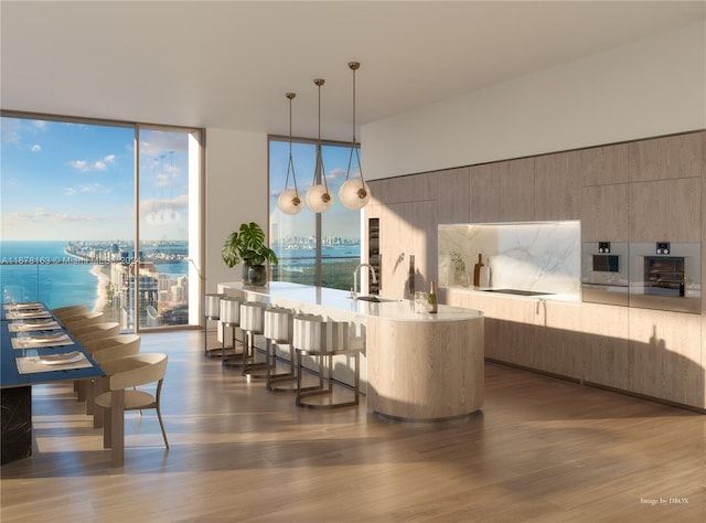 dining room featuring floor to ceiling windows, dark hardwood / wood-style floors, sink, and a water view