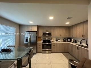 kitchen with light brown cabinetry, sink, appliances with stainless steel finishes, and light tile patterned floors