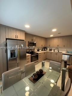 kitchen with tile patterned floors, sink, appliances with stainless steel finishes, and tile counters