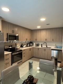 kitchen with light brown cabinetry, sink, stainless steel appliances, and light tile patterned floors