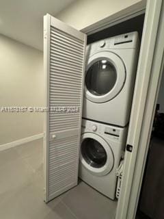 laundry room with tile patterned flooring and stacked washing maching and dryer