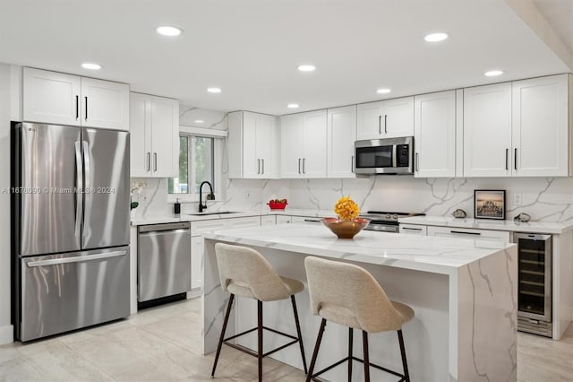 kitchen with white cabinetry, appliances with stainless steel finishes, a center island, and beverage cooler