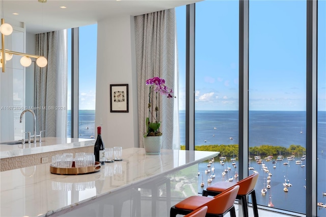 dining space with a baseboard heating unit, a water view, and floor to ceiling windows