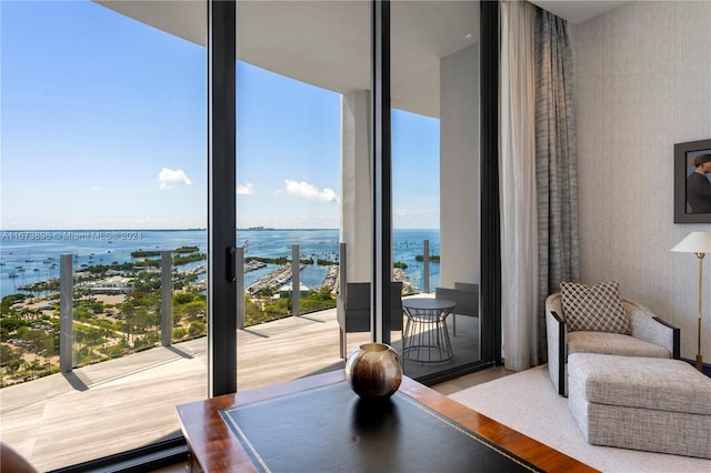 interior space featuring wallpapered walls, expansive windows, a water view, and wood finished floors