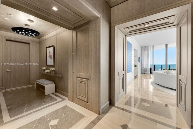interior space featuring a water view, baseboards, marble finish floor, and a freestanding tub