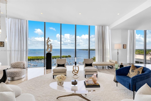 living room with a water view, a wall of windows, and wood finished floors