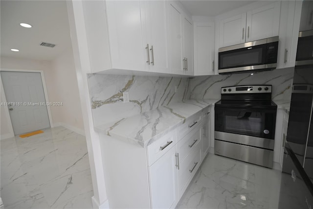 kitchen with light stone countertops, white cabinetry, backsplash, and appliances with stainless steel finishes