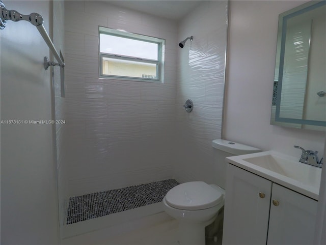 bathroom featuring vanity, toilet, and a tile shower