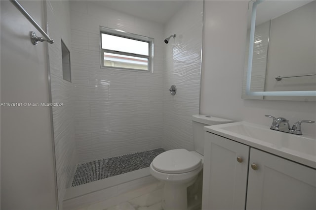 bathroom with vanity, toilet, and a tile shower