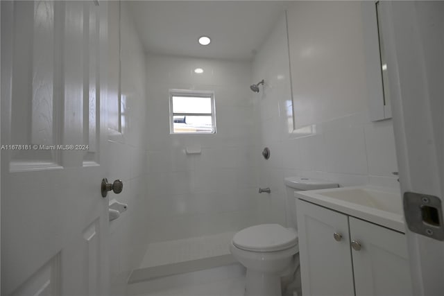 bathroom featuring tiled shower, vanity, tile walls, and toilet