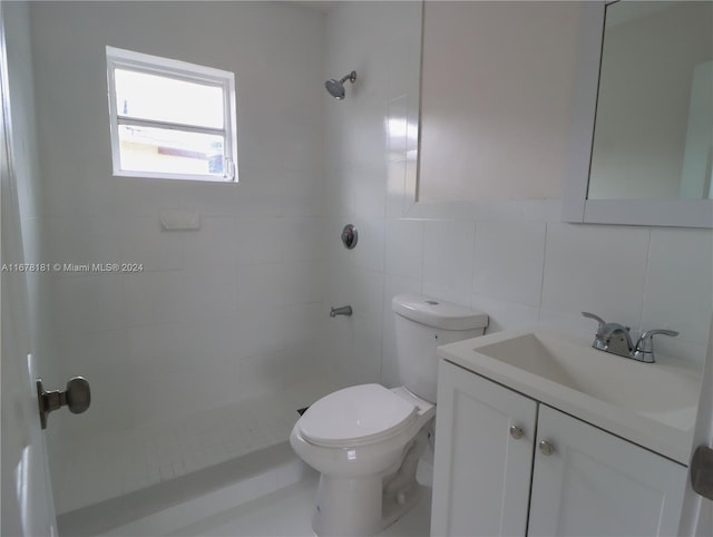 bathroom with vanity, toilet, tiled shower, and tile walls