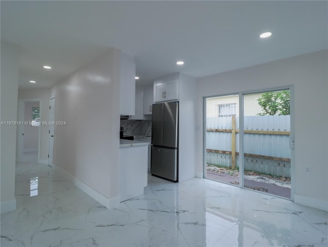 kitchen with tasteful backsplash, white cabinetry, and stainless steel refrigerator