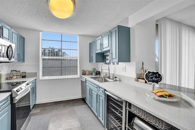 kitchen featuring a textured ceiling, stainless steel appliances, wine cooler, and sink