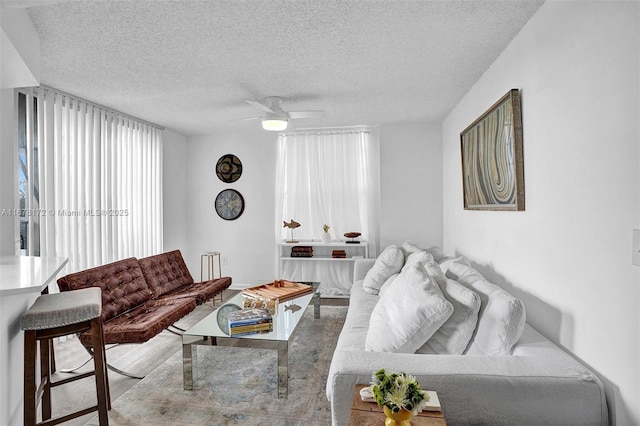 living room featuring ceiling fan and a textured ceiling