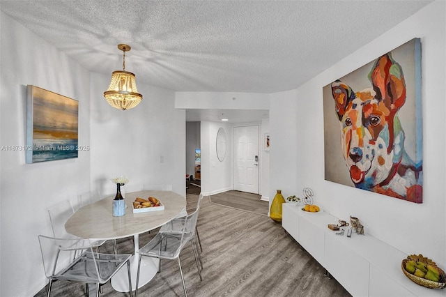 dining space with hardwood / wood-style floors, a textured ceiling, and an inviting chandelier