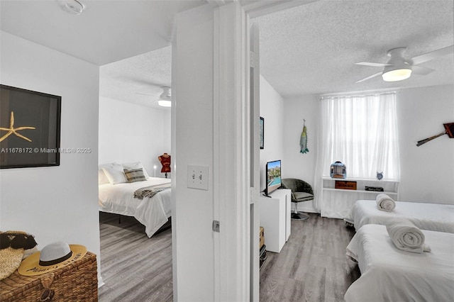 bedroom with ceiling fan, light hardwood / wood-style floors, and a textured ceiling