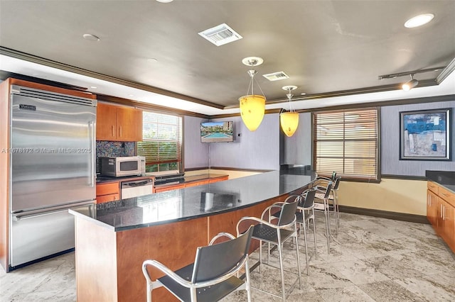 kitchen with hanging light fixtures, a kitchen breakfast bar, a raised ceiling, crown molding, and appliances with stainless steel finishes