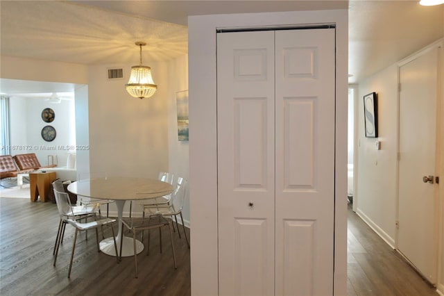 dining area with dark hardwood / wood-style floors and an inviting chandelier