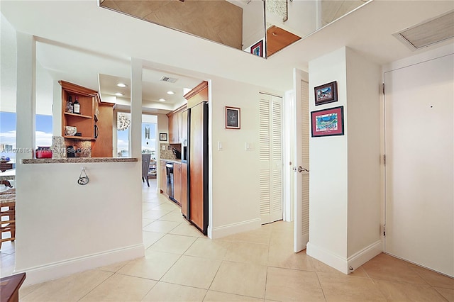 kitchen with kitchen peninsula, stainless steel fridge with ice dispenser, and light tile patterned floors