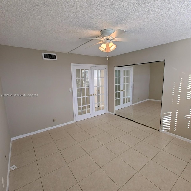 tiled empty room featuring ceiling fan, a textured ceiling, and french doors