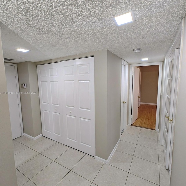 hallway with light tile patterned floors and a textured ceiling