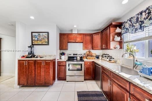 kitchen with light stone countertops, sink, light tile patterned flooring, and appliances with stainless steel finishes