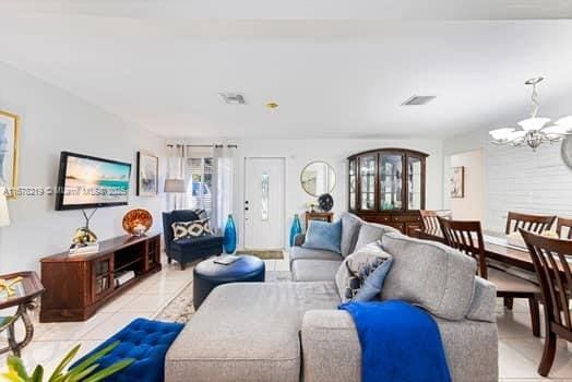 tiled living room featuring an inviting chandelier